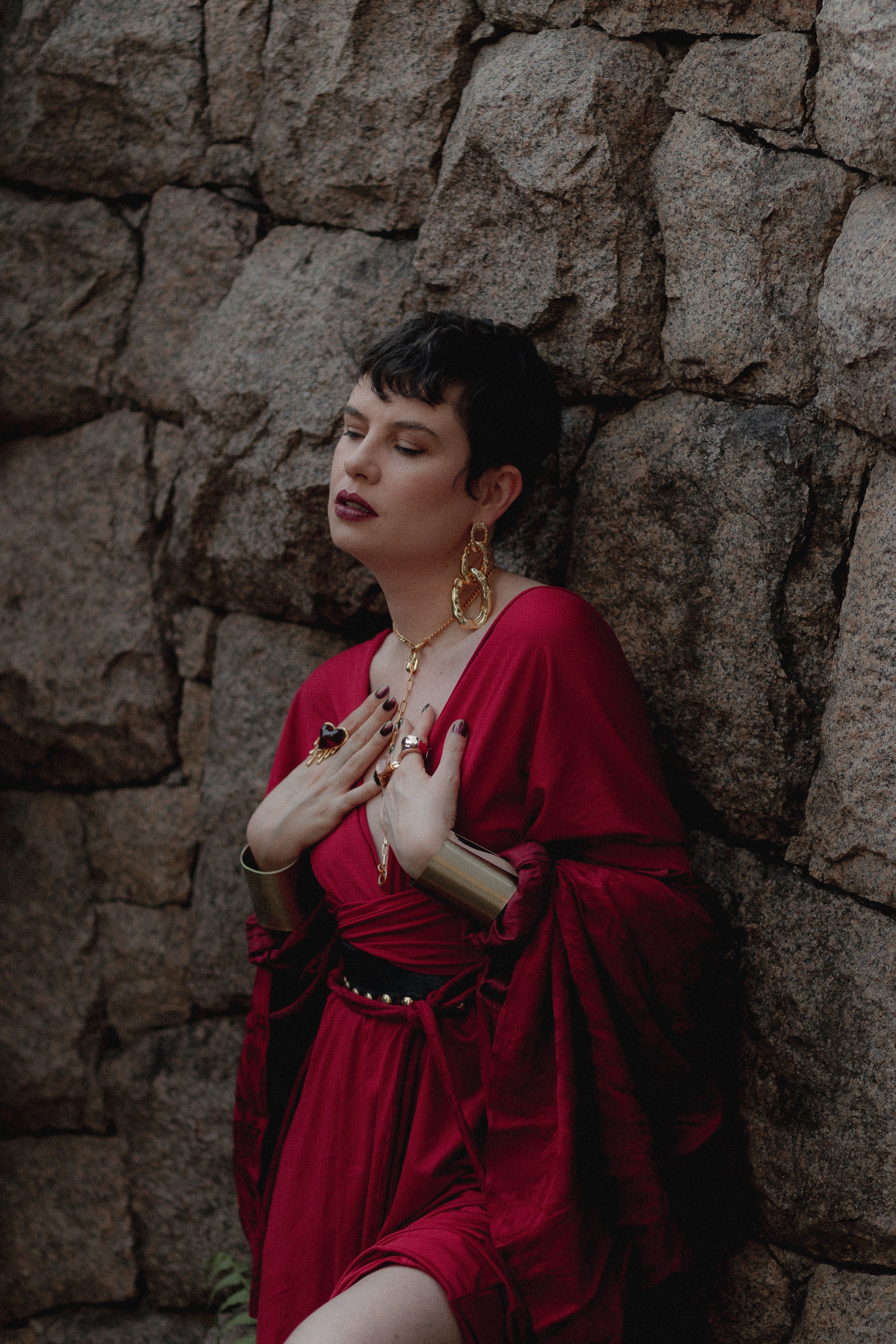 Woman in Elegant Red Dress Leaning on Stone Wall · Free Stock Photo
