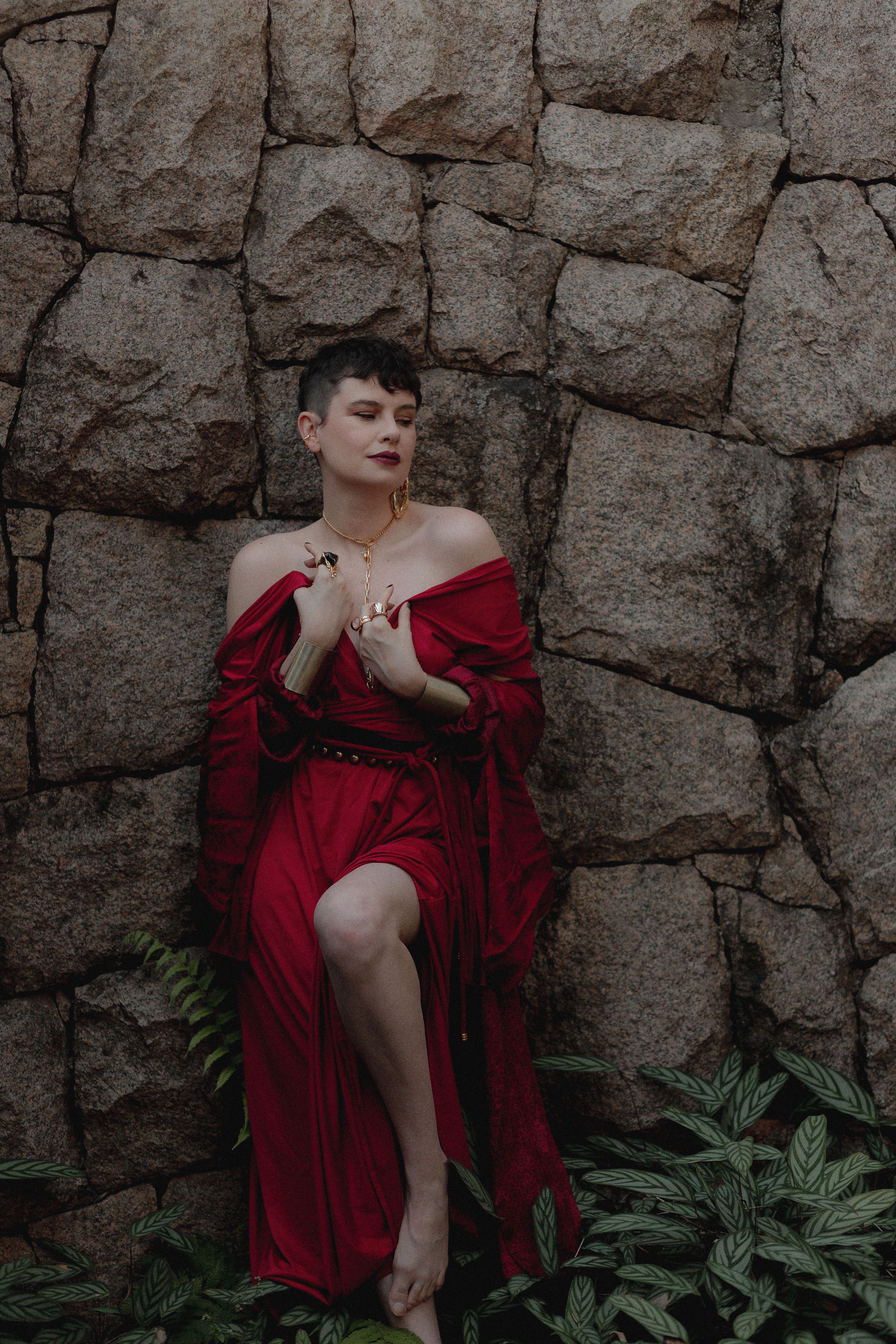 Woman in Red Dress Leaning Against Stone Wall · Free Stock Photo