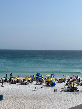 Vibrant beach scene in Arraial do Cabo, Brazil with colorful umbrellas and clear blue water.
