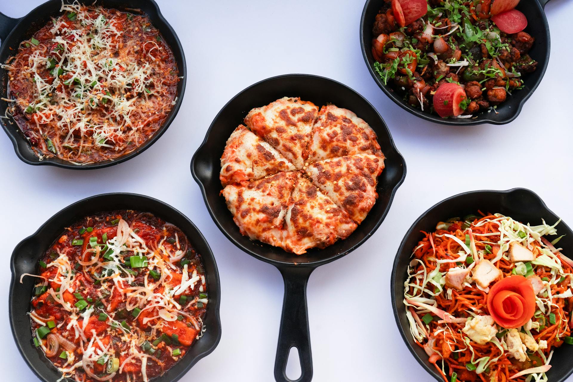 Five diverse skillet meals showcasing various cuisines, beautifully styled from above.