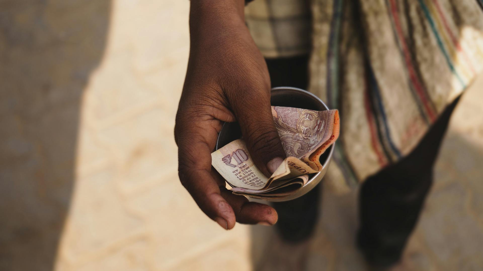 A close-up of a hand holding Indian currency notes, highlighting economic themes.