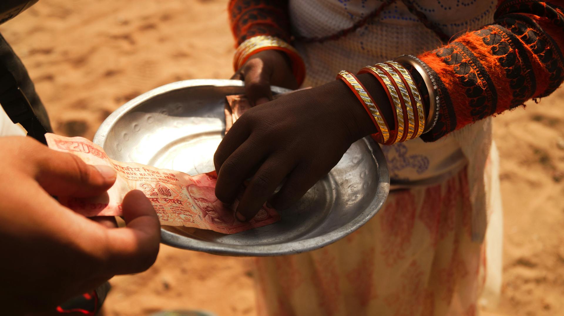 Two individuals exchanging Indian currency outdoors, highlighting cultural attire and transactional theme.