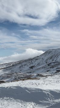 A breathtaking view of a snow-covered mountain range under a bright, cloudy sky.