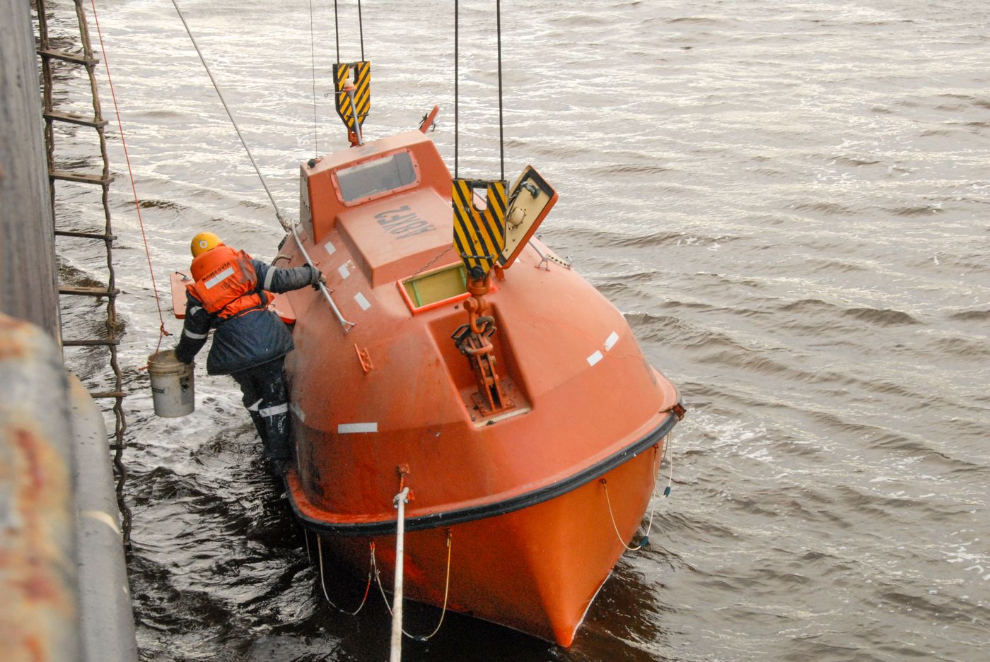 Marine safety drill with an orange lifeboat at sea