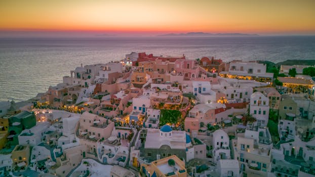 A stunning aerial view of Oia, Santorini with vibrant sunset colors over the Aegean Sea.
