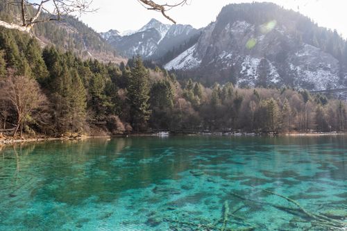 Free Breathtaking view of a serene alpine lake with clear turquoise waters surrounded by snow-capped mountains. Stock Photo