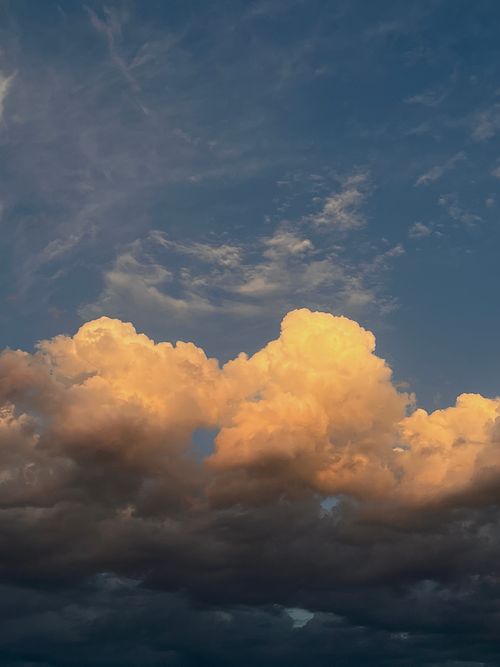 Free Vibrant cumulus clouds with a golden sunset light against a deep blue sky. Stock Photo