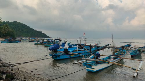 Free Blue traditional fishing boats anchored along the peaceful coast under cloudy skies. Stock Photo
