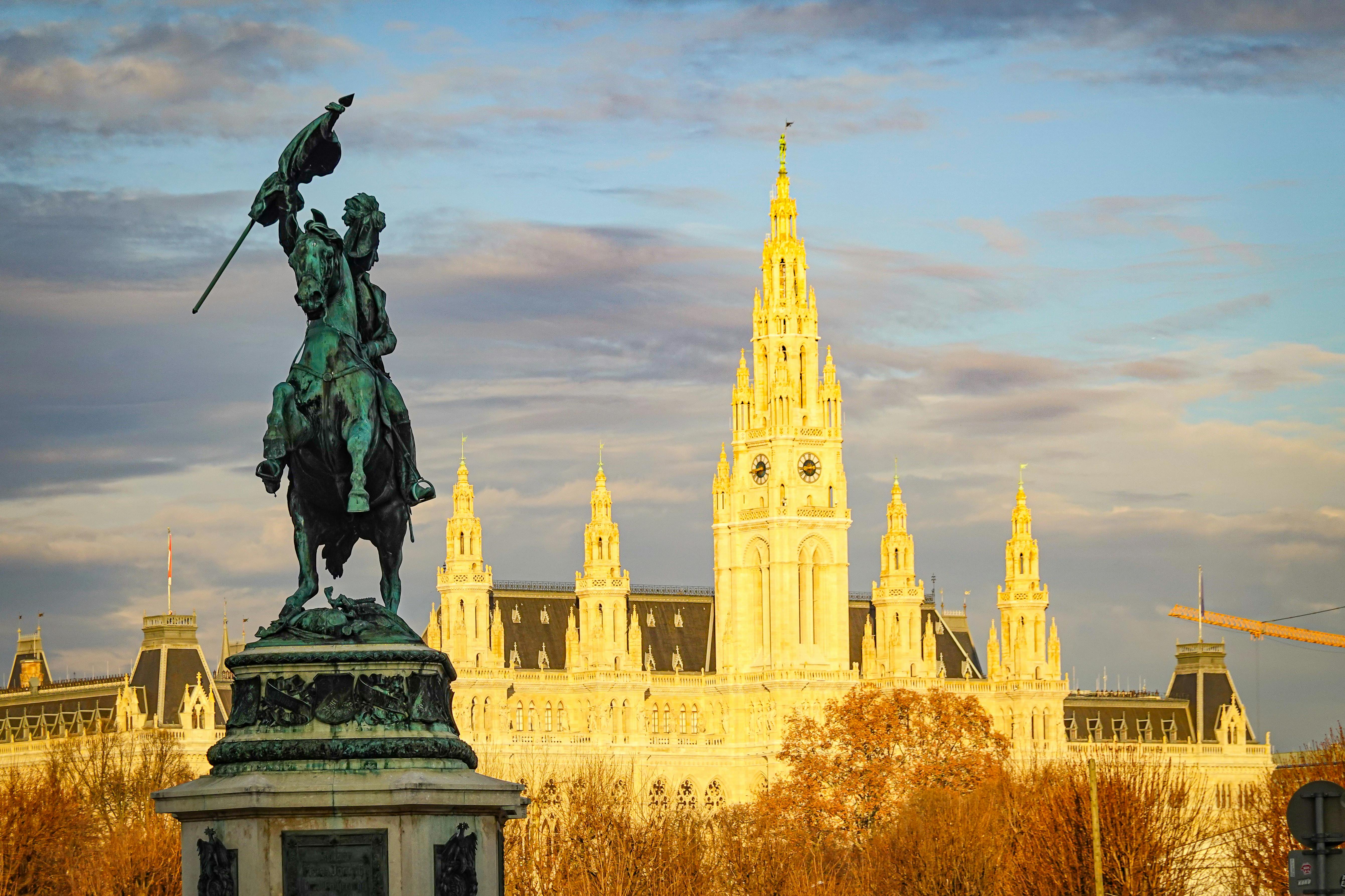 Captivating view of an equestrian statue with the iconic Vienna Rathaus at sunrise.