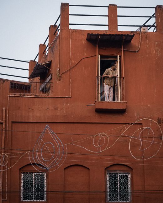 A person looks out from a balcony in old heritage architecture in Kolkata, India.