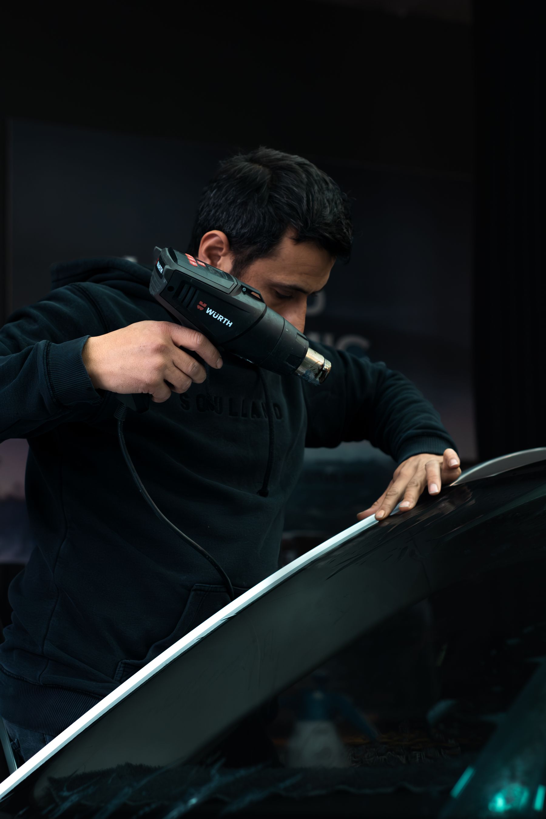 Automotive technician working on a vehicle windshield