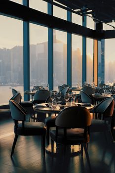 Beautiful restaurant interior with city skyline view during sunset, elegant and sophisticated.