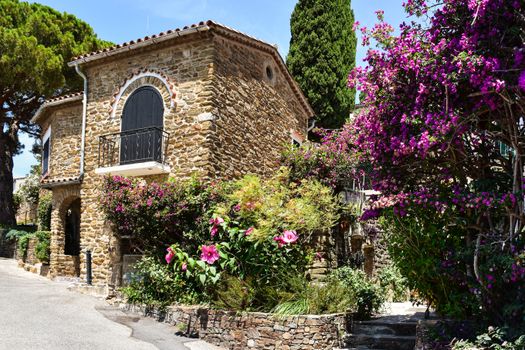 Beautiful stone house surrounded by vibrant flowers in Bormes-les-Mimosas, France.