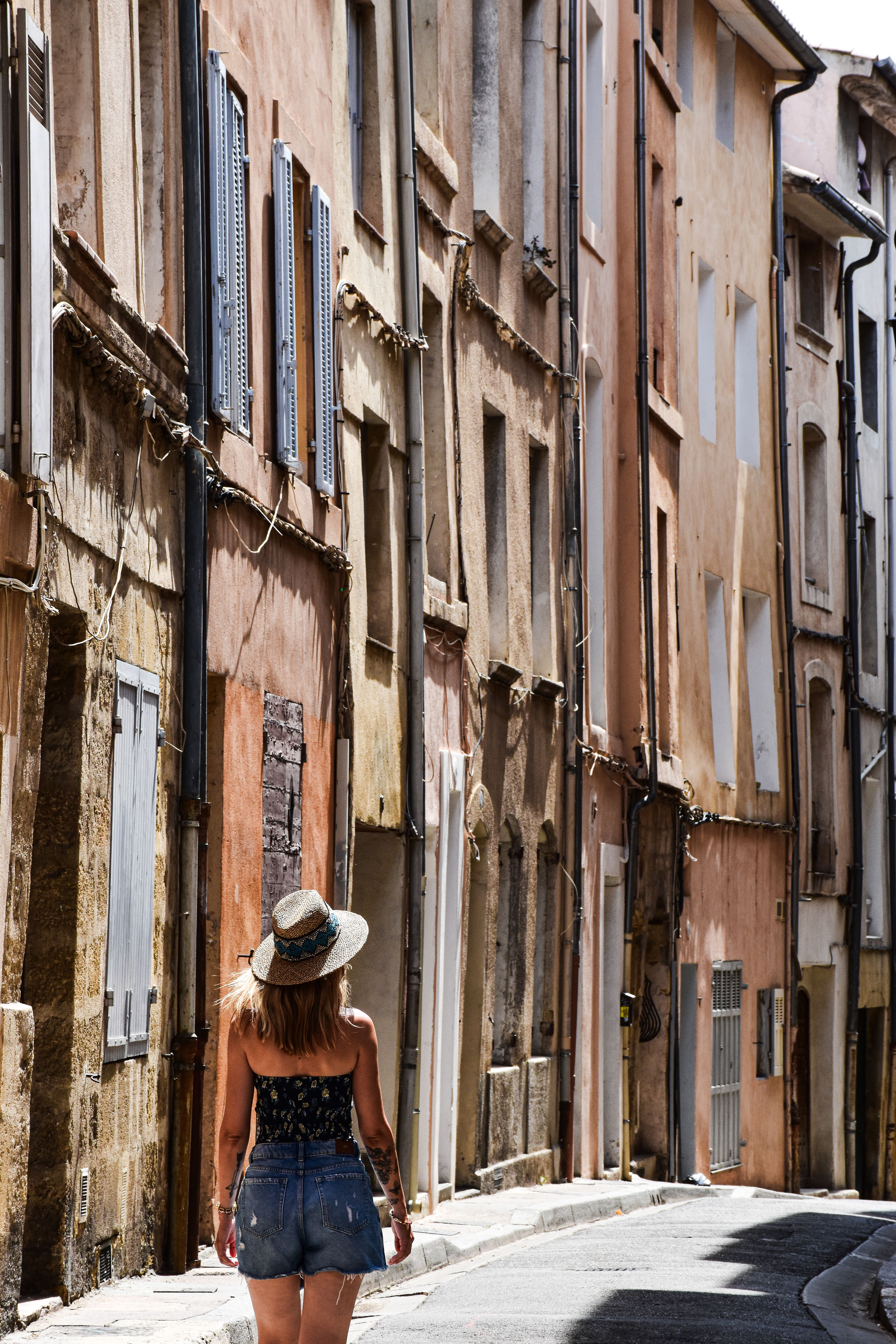 A woman strolls along a picturesque street in Aix-en-Provence, France, enjoying the charming architecture.