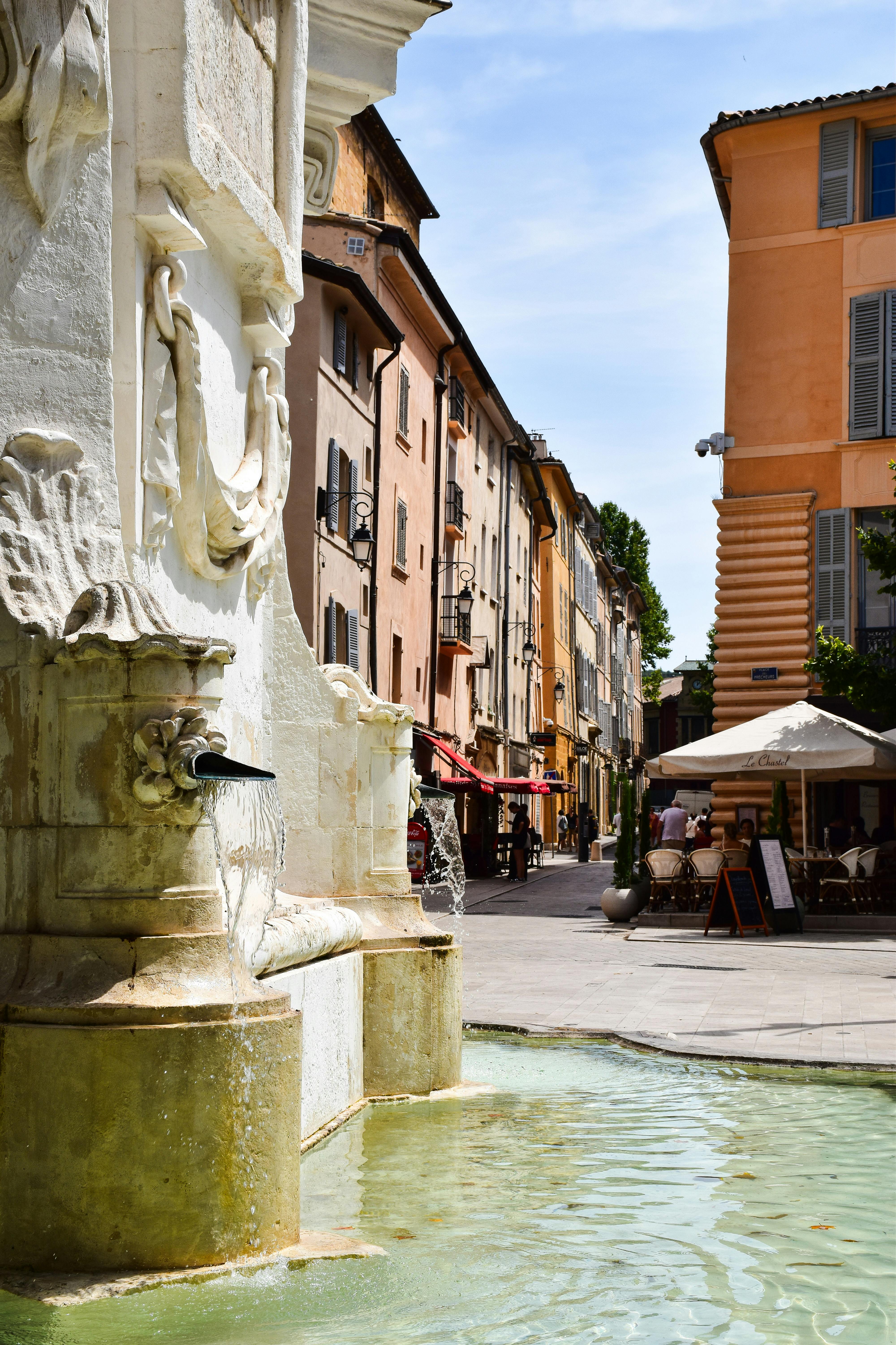 Discover a picturesque street with a vintage fountain in Aix-en-Provence, France.