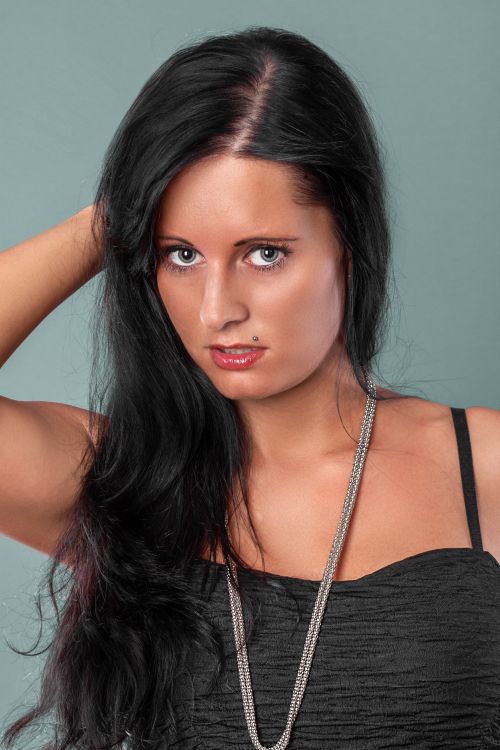 Free Stylish portrait of a woman with striking black hair in a studio setting. Stock Photo