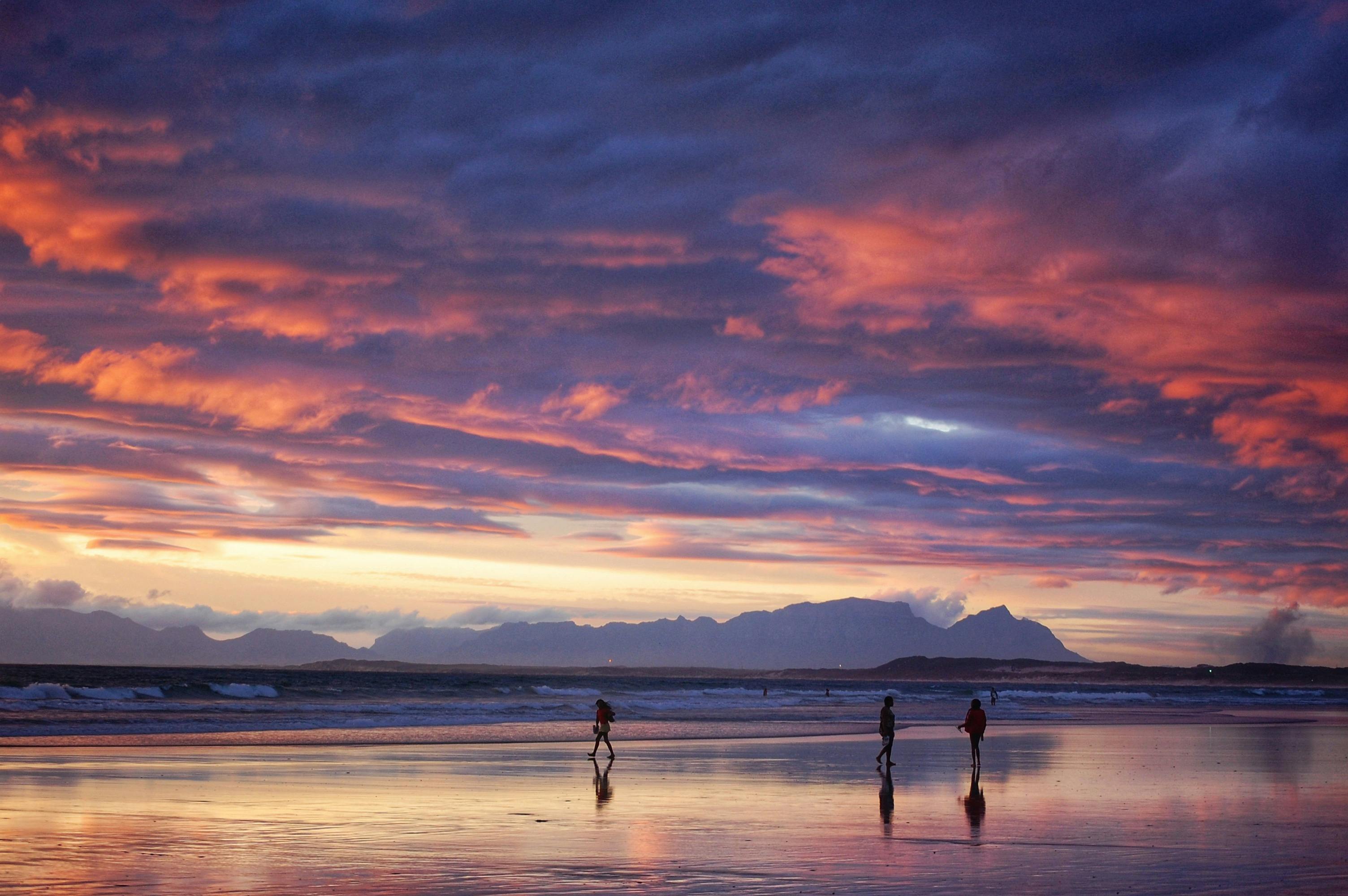 Majestic sunset over the ocean with vivid colors and silhouettes of people on the beach. Perfect moment captured.