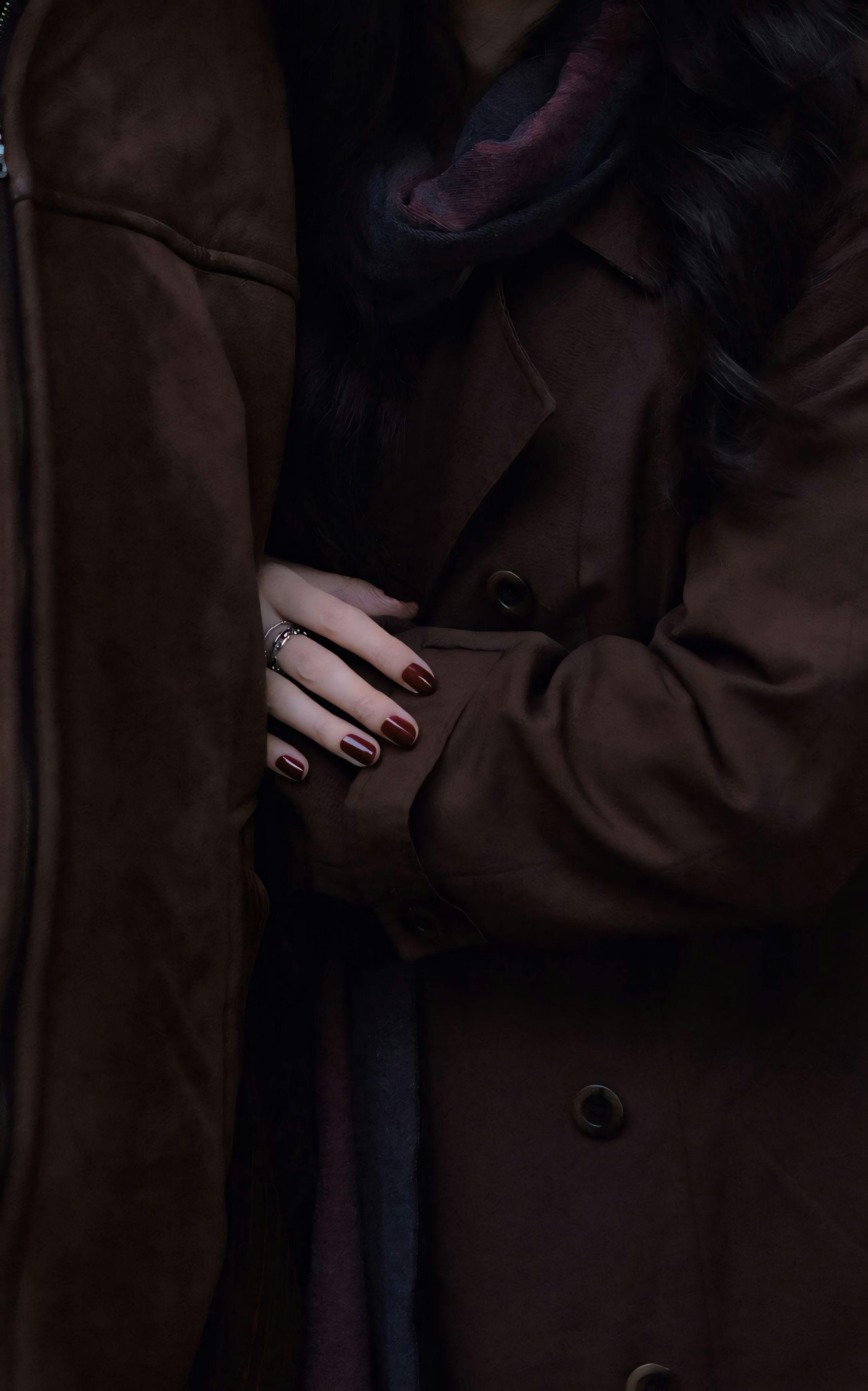 A close-up shot showcasing the texture and warmth of brown coats with arms intertwined, conveying a sense of intimacy and warmth.