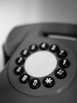 Close-up of a classic rotary dial telephone in black and white, highlighting its vintage design.