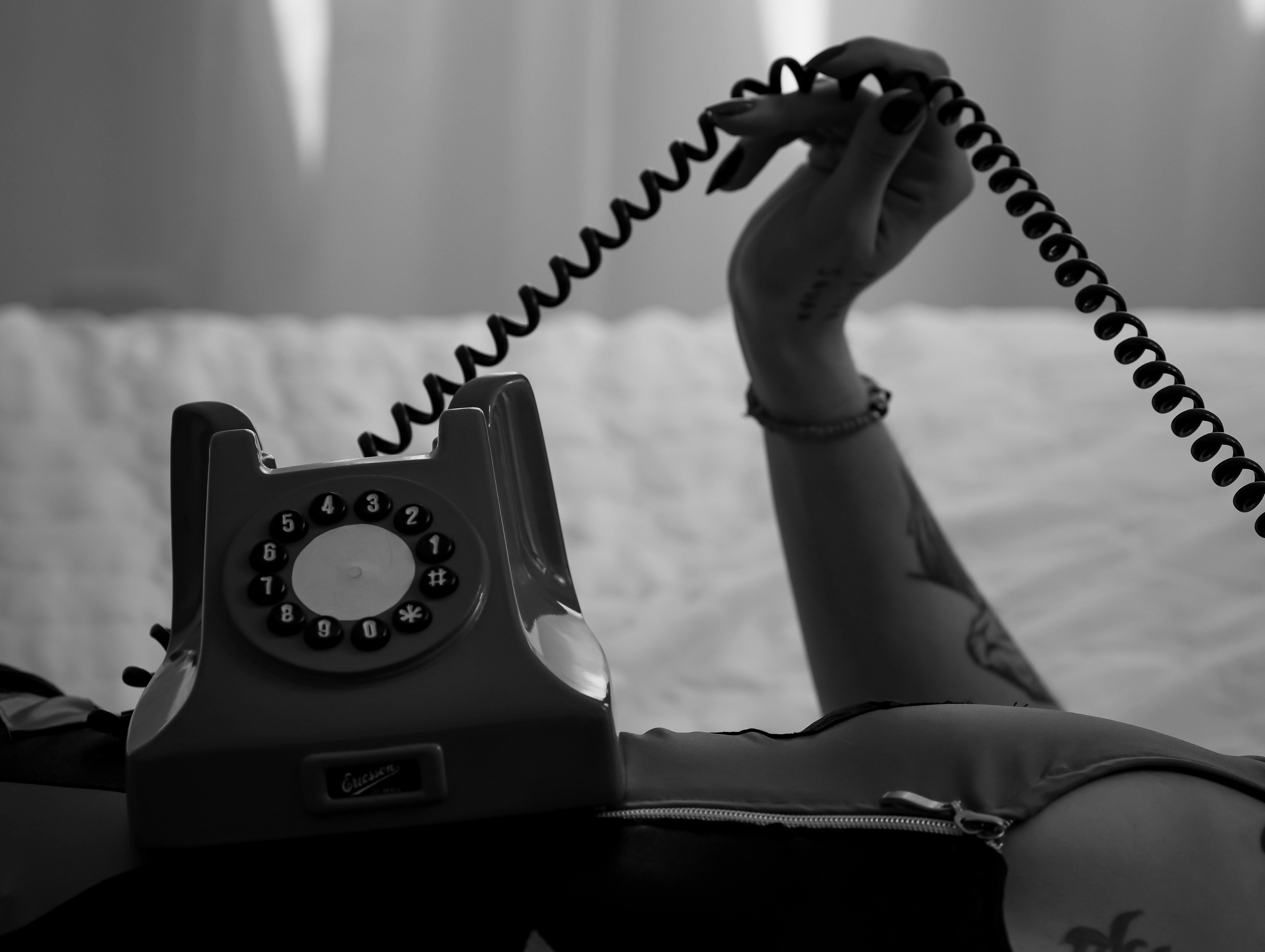 Kostnadsfria Svartvitt foto med en vintage telefon med roterande urtavla och en mystisk hand som håller i luren. Stock foto