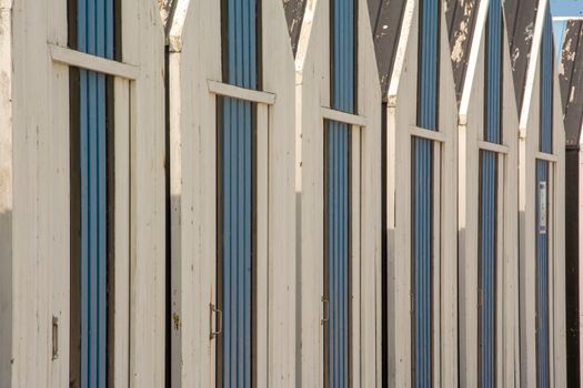 A row of rustic wooden beach huts with blue stripes. Perfect for summer themes.