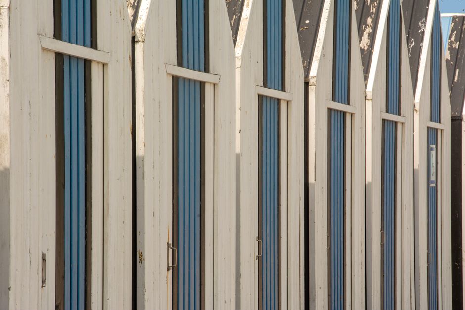A row of rustic wooden beach huts with blue stripes. Perfect for summer themes.