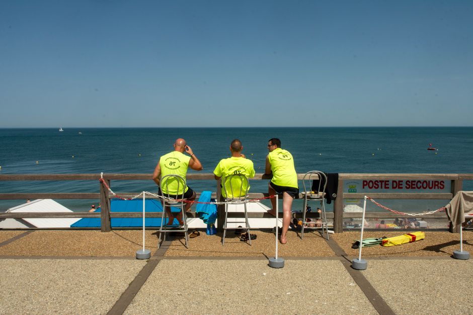 Lifeguards overlooking the serene Étretat beach on a sunny day in Normandy, France.