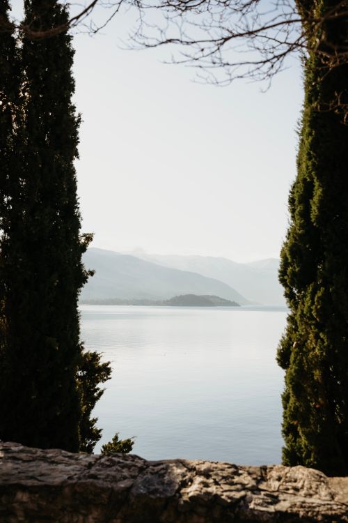 Free Serene view of Lake Ohrid framed by trees, captured in Ohrid, North Macedonia. Stock Photo
