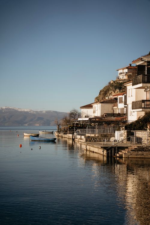 Free Peaceful lakeside scene in Ohrid, Macedonia with boats and hillside houses. Stock Photo