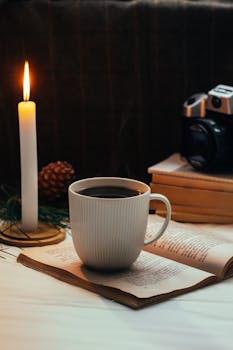Warm, inviting scene with coffee, candle, books, and camera indoors.