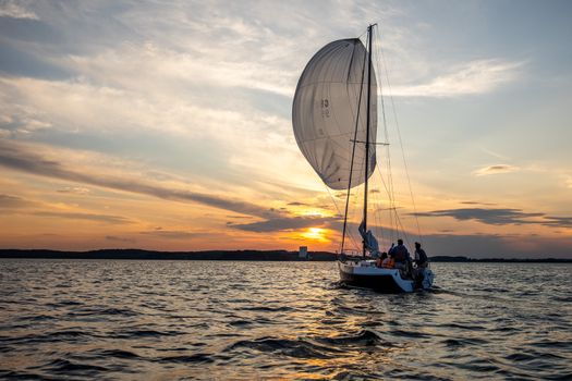 A yacht sails gracefully during sunset, capturing the romance and tranquility of evening sailing.