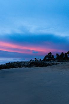A scenic beach in Kerala, India at sunset, with vibrant skies and palm trees.