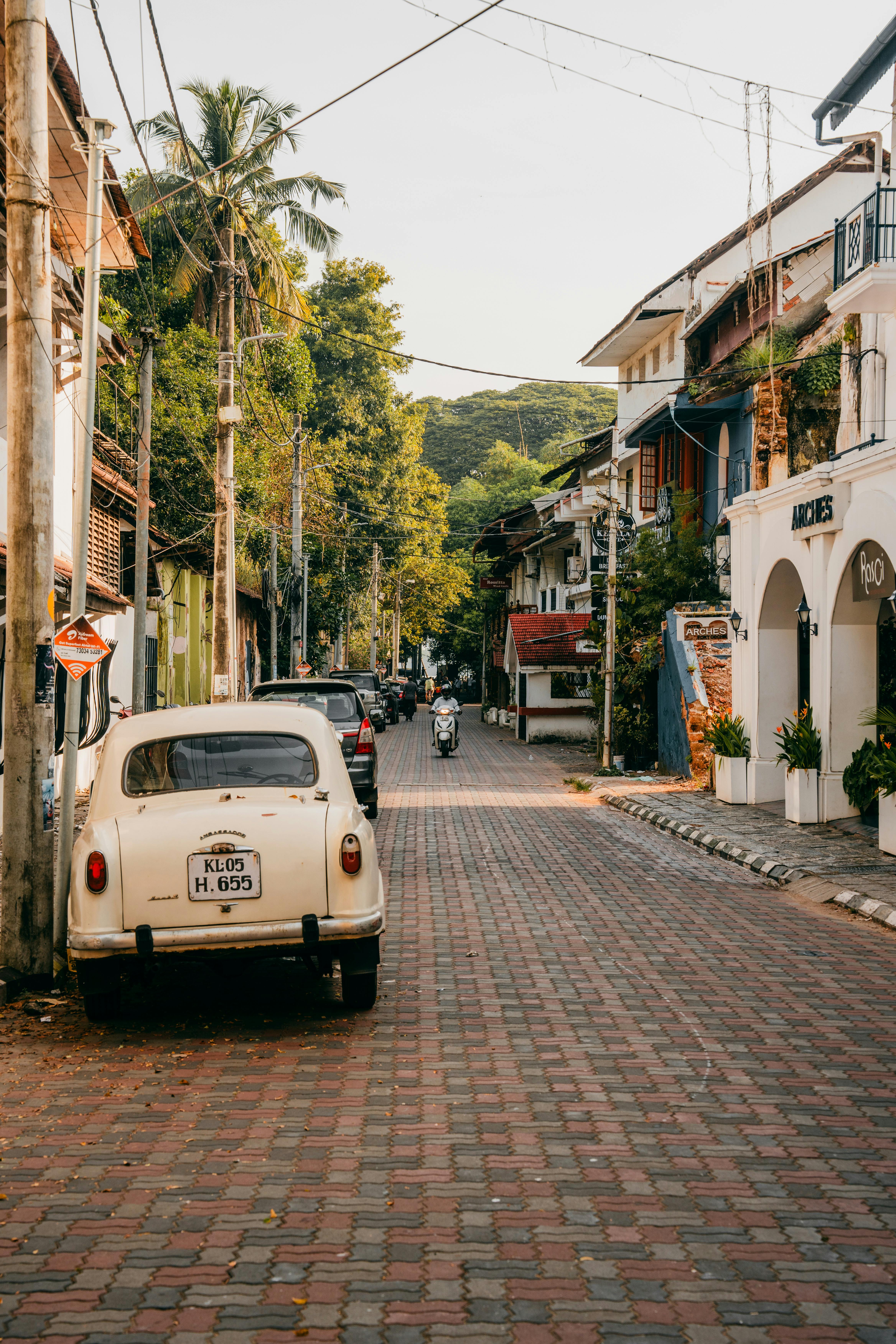 Scenic street in Kerala with vintage car and colonial architecture.