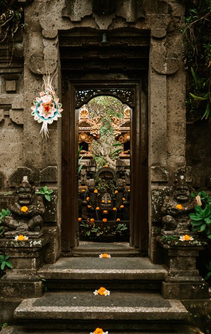 Intricate Balinese temple entrance adorned with vibrant floral offerings in Bali, Indonesia.