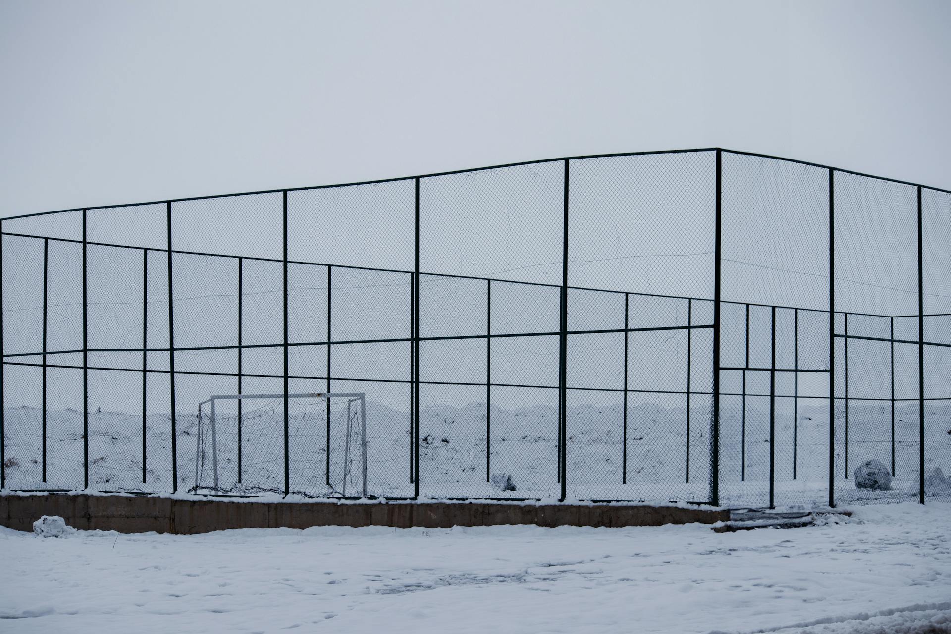 A serene snowy football field enclosed with wire fences in Palu, Elazığ, Türkiye.