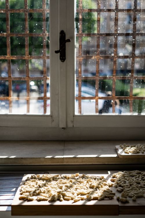 Free Fresh homemade pasta drying on a sunlit window sill, casting cozy shadows indoors. Stock Photo