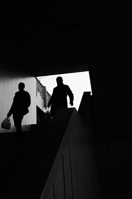 Black and white street photograph of silhouetted figures walking up a staircase.