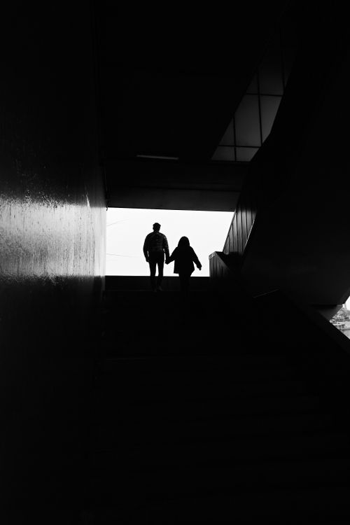 Free Black and white silhouette of a couple ascending stairs, creating a mysterious and artistic ambiance. Stock Photo