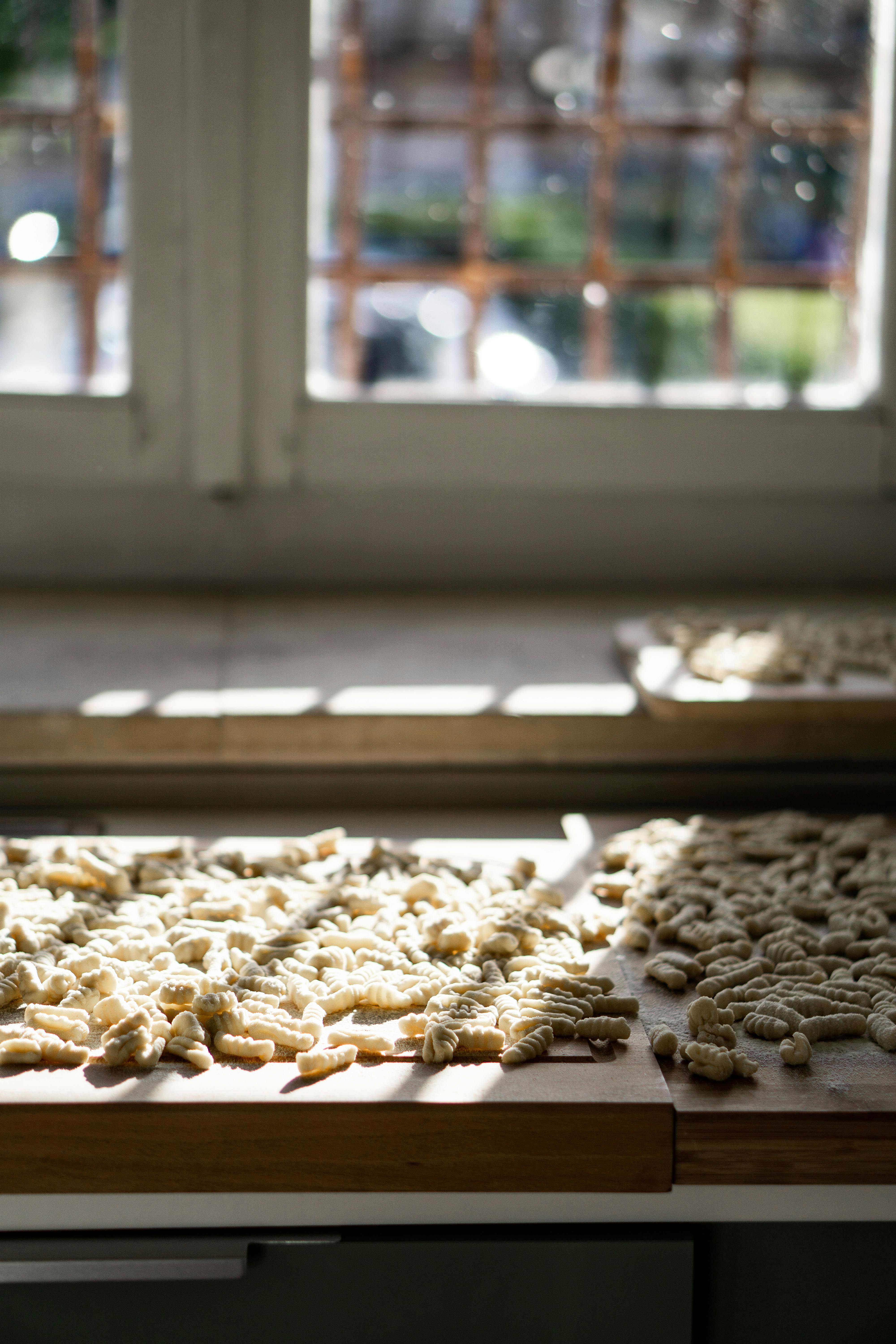 Delicious homemade pasta drying on a wooden board with natural sunlight streaming in through the window.