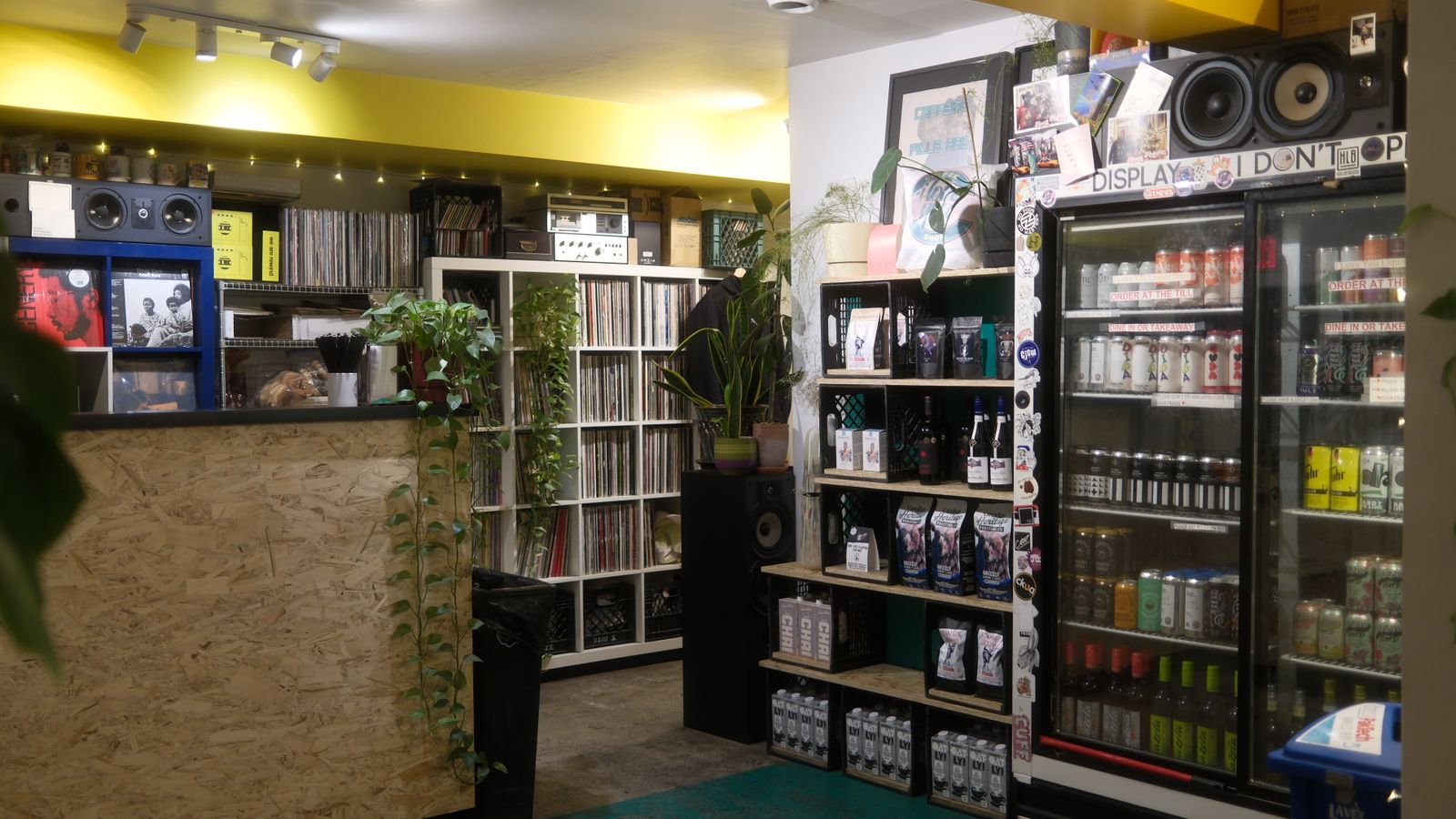 Warm, inviting record shop showcasing vinyl collection, beverages, and plants. Ideal cozy vibe.