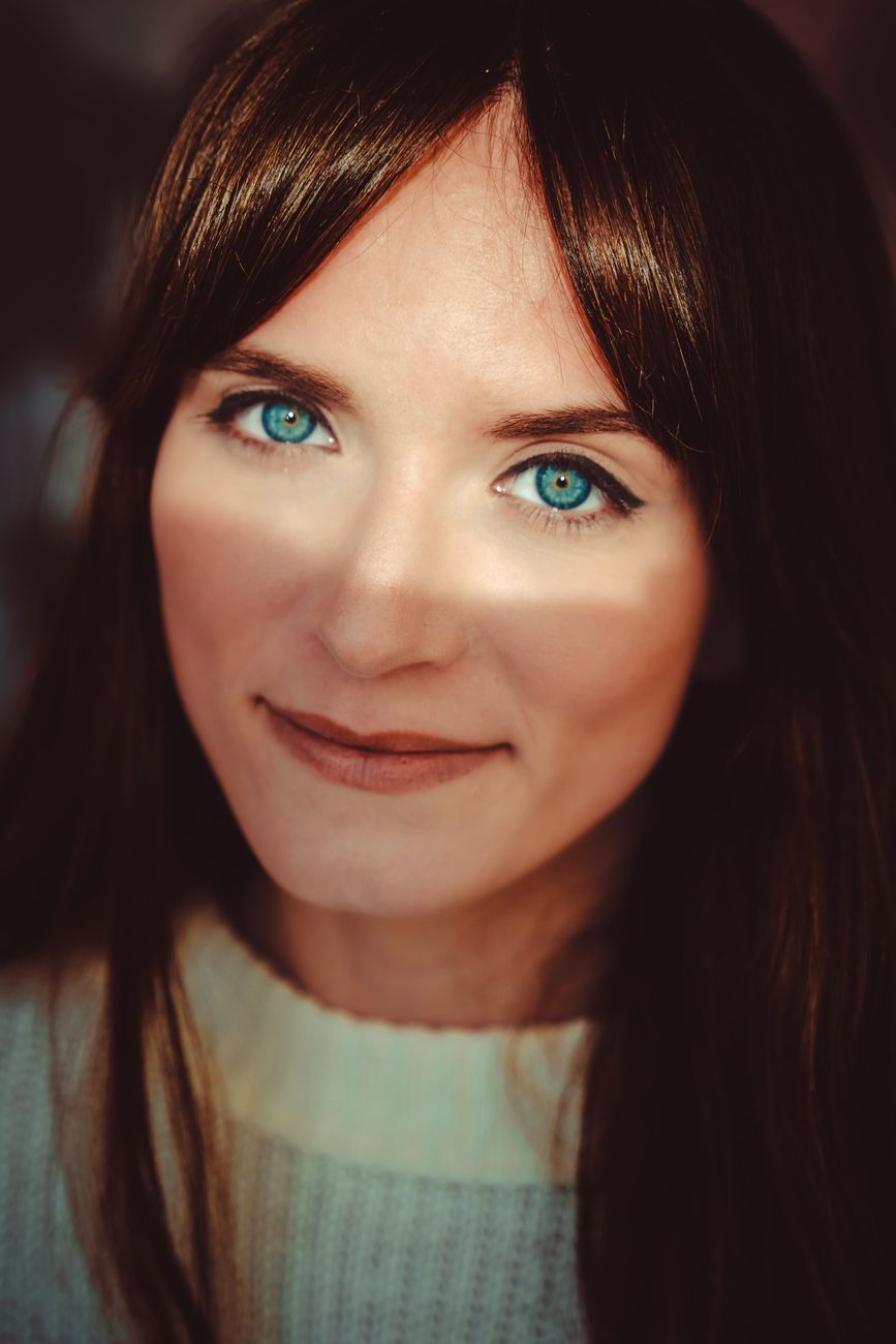 Intimate close-up portrait of a woman with striking blue eyes and a soft smile.