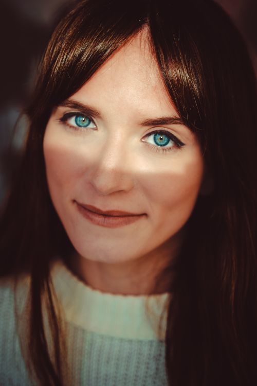 Free Intimate close-up portrait of a woman with striking blue eyes and a soft smile. Stock Photo
