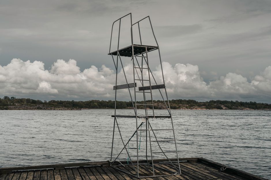 An empty lifeguard tower stands on a pier by a calm and cloudy seaside, offering a serene coastal view.