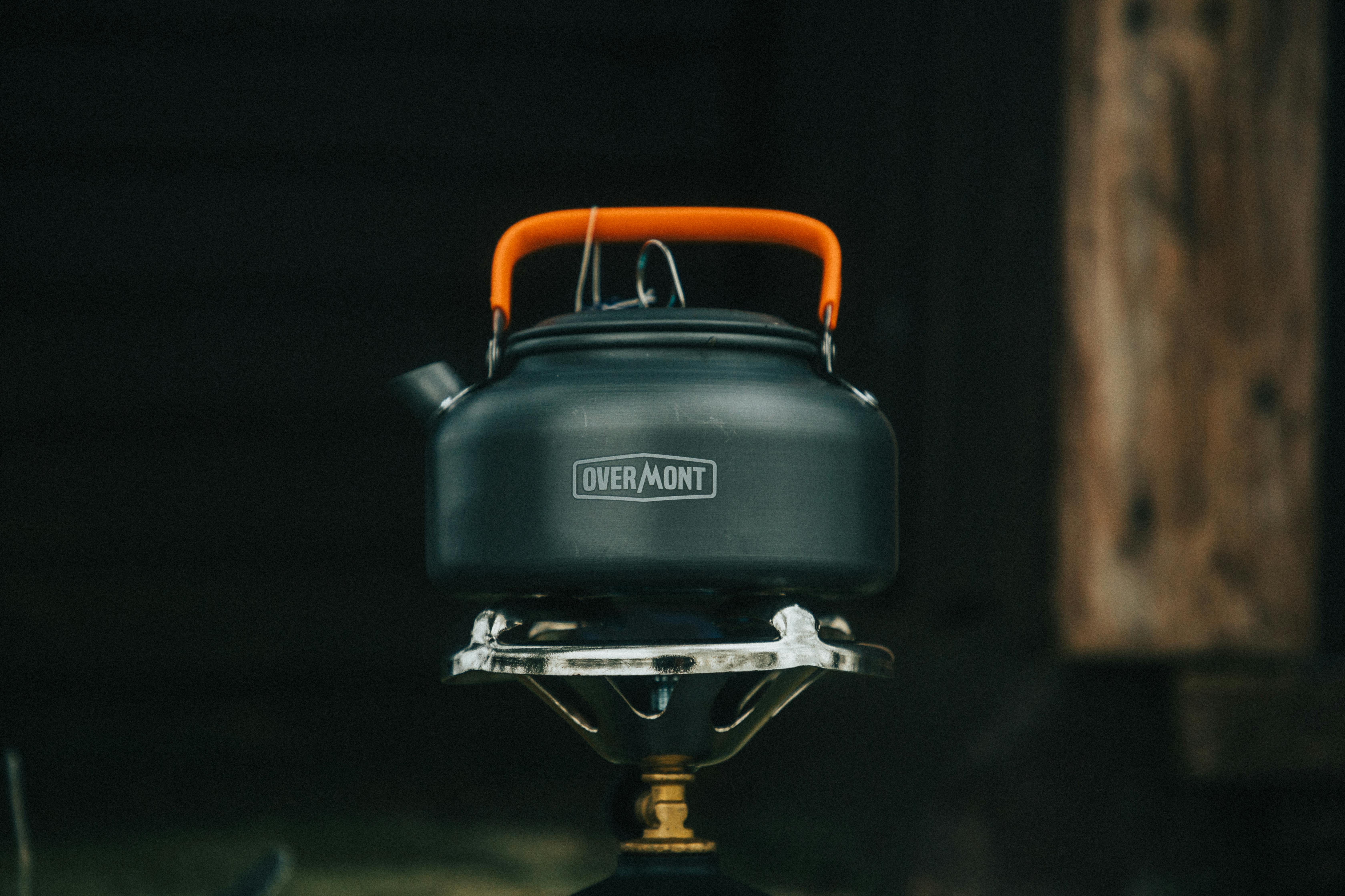 A compact camping kettle sitting on a portable stove, ideal for outdoor adventures.