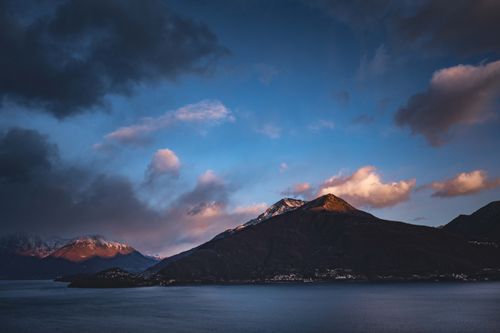 Free A breathtaking mountain landscape with dramatic clouds illuminated by the sunset light. Stock Photo