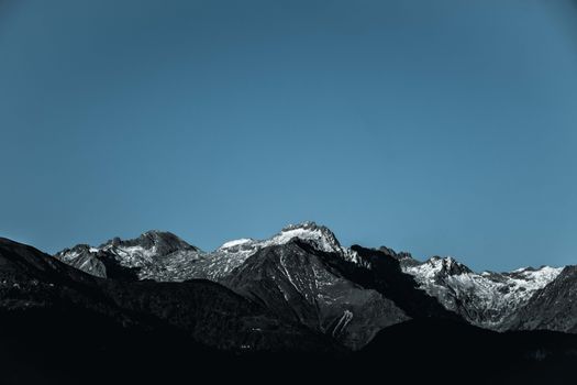 An awe-inspiring view of a snow-capped mountain range under a clear blue sky.