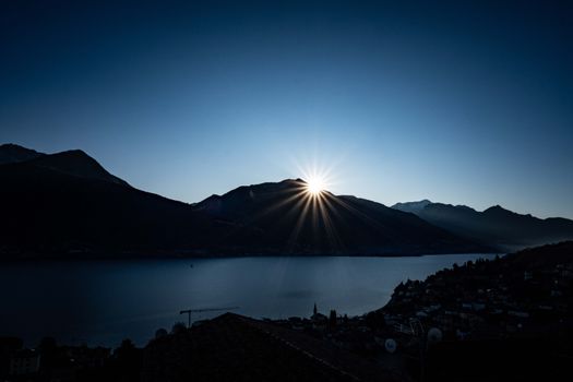 Beautiful sunrise over mountain ridge reflecting on tranquil lake waters.