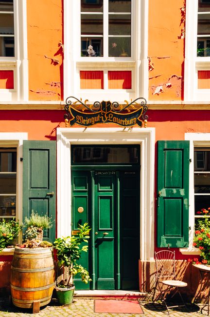 Bright facade with green doors and barrel decor in Bernkastel-Kues, Germany.