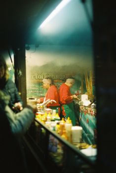 Atmospheric Berlin Christmas market scene with vendors preparing festive food at night.