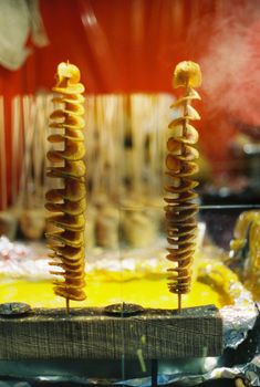 Delicious spiral potato skewers on display at a Berlin Christmas market during nighttime.